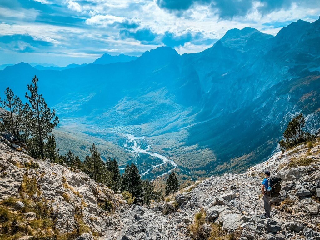 Hiker descending a rocky trail towards the Valbona valley
